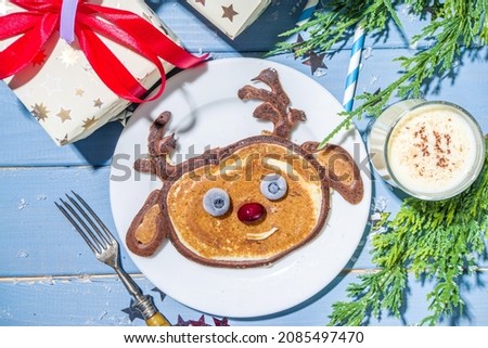Christmas New Year morning breakfast, kids festive brunch snack. Funny reindeer pancakes made with with berries, chocolate and vanilla dough