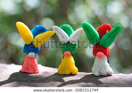 Figures of Easter gnomes with ears made of plasticine on a colored background.