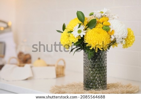 Bouquet of beautiful chrysanthemum flowers on countertop in kitchen, space for text