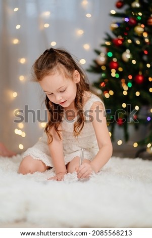 cute kid girl writes a letter to Santa Claus at the Christmas tree. tradition to give gifts to celebrate the new year.
