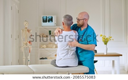 A Doctor Conducts a Physiotherapy Session After a Medical Trauma with a Man in the Modern Rehabilitation Clinic. Rehabilitation Concept Royalty-Free Stock Photo #2085575083