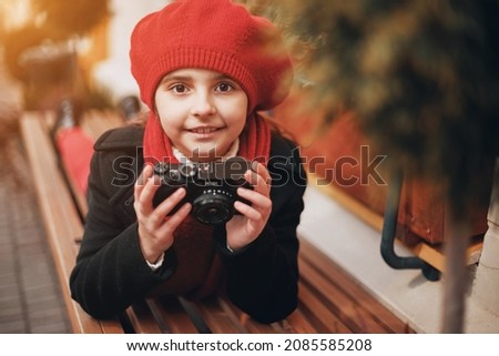 beautiful girl in a red beret and scarf takes pictures on the city street. High quality photo