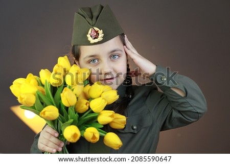 Portrait of little girl in green uniform with bouquet of yellow flowers. Happy veteran day celebration. Memorial day respect and victory concept. Veterans Day. Holiday and school uniform