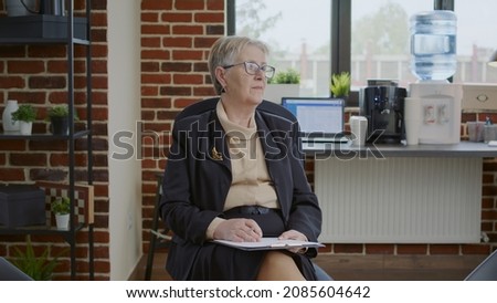 Psychiatrist waiting on people to attend group therapy in space with aa meeting sign on board. Woman therapist holding clipboard and preparing for rehabilitation and counseling session.