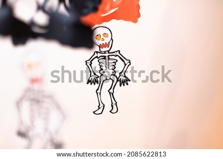 Selective focus. Paper skeletons garland on white wall. Halloween background. Day of Dead. Copy space for your text.