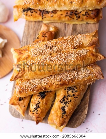 Homemade pies with cheese sprinkled with black and white sesame served on a wooden board