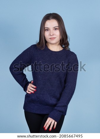 brunette lady in blue jumper on blue background.