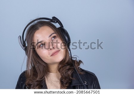 a young girl in a leather jacket, listening to music on headphones