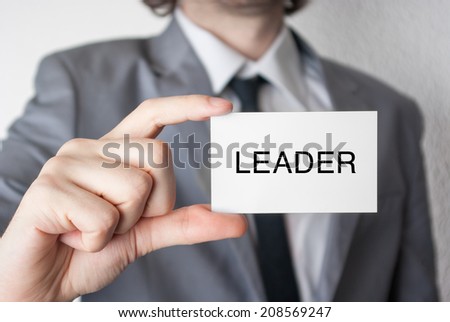 Leader. Businessman in suit with a black tie showing or holding business card