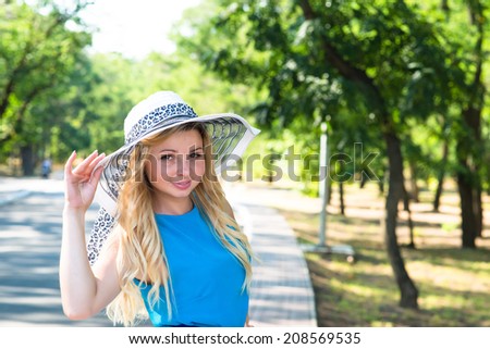 young woman in a blue dress and a hat park