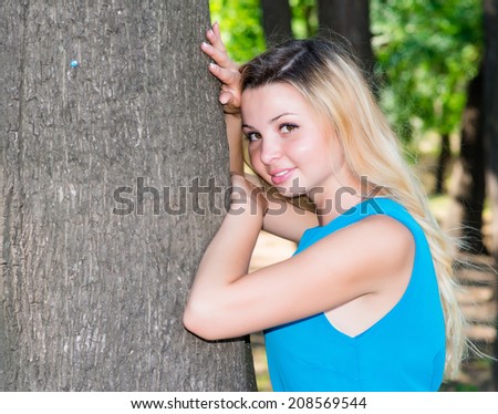 young woman leaning on a tree