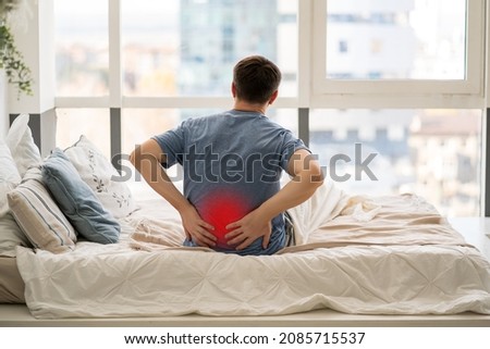 Back pain, kidney inflammation, man suffering from backache at home, painful area highlighted in red Royalty-Free Stock Photo #2085715537