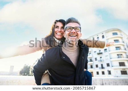 Adult couple in love having fun on city street - Husband and wife enjoying weekend outside activities on vacation - Happy lifestyle and holidays concept