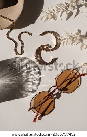 Aesthetic luxury fashion boutique branding composition. Elegant boho women's jewelry and accessories: sunglasses, earrings, bracelet, glass sunlight shadow on white table. Flat lay, top view Royalty-Free Stock Photo #2085739432