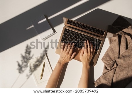 Flatlay of person hands working on laptop computer. Aesthetic bohemian home office workspace. Work at home. Notebook, pampas grass sunlight shadow on table. Flat lay, top view Royalty-Free Stock Photo #2085739492