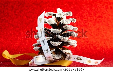 decorated pine cone as christmas tree decoration on red background