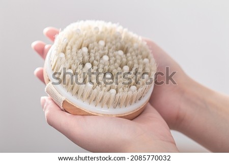 Dry massage brush made of natural materials in a female hands.