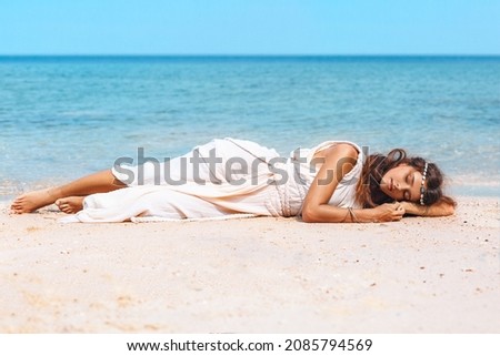 beautiful young stylish woman lying on sand on the beach