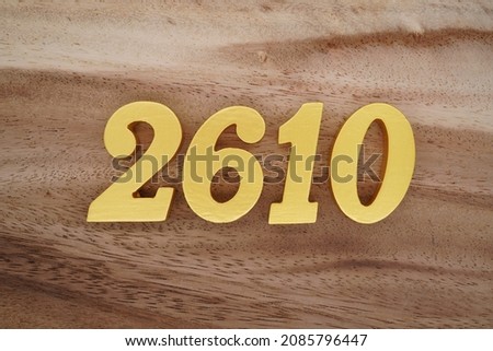 Golden Arabic numerals 2610 on a dark brown to white wood grain background.