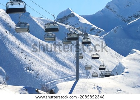 An empty chairlift on a background of snowy slopes and blue sky. Winter landscape of the ski resort. Winter sports during the vacations