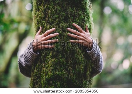 Nature lover hugging trunk tree with green musk in tropical woods forest. Green natural background. Concept of people love nature and protect from deforestation or pollution or climate change Royalty-Free Stock Photo #2085854350