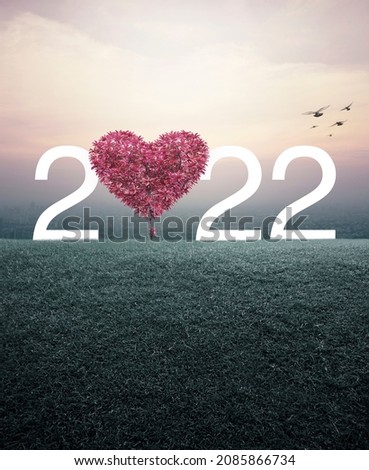 Red tree in the shape of heart love with 2022 white text on green grass field over aerial view of cityscape at sunset, vintage style, Happy valentines day 2022 cover concept