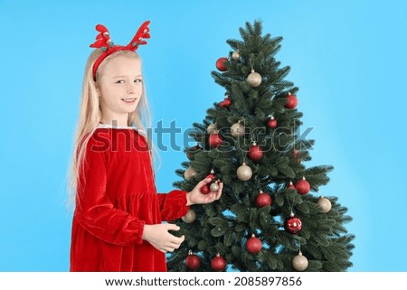 Cute little girl on blue background with Christmas tree