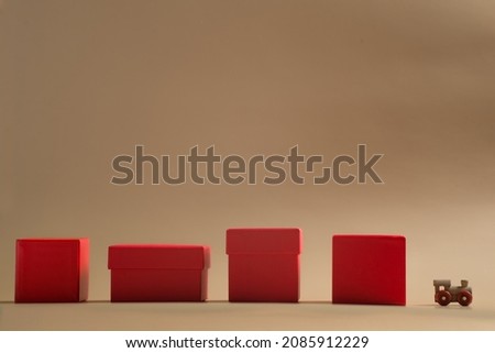 small wooden train with red gift boxes in a row on a beige background