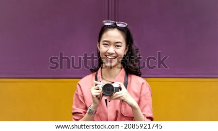 a happy young woman holding a camera  