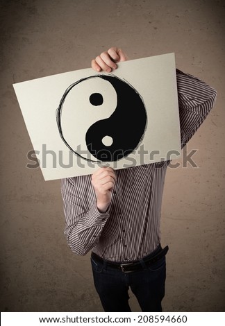 Businessman holding a paper with a yin-yang symbol on it in front of his head