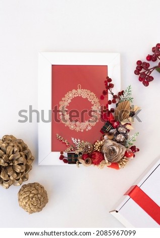 white blank photo frame with new year decoration. Gold cone, cocina flower around it. Christmas frame