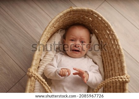 a 6-month-old baby lies in a crib in the nursery with white clothes on her back and laughs, looks at the camera, the morning of the child, the concept of children's goods. high-quality photography