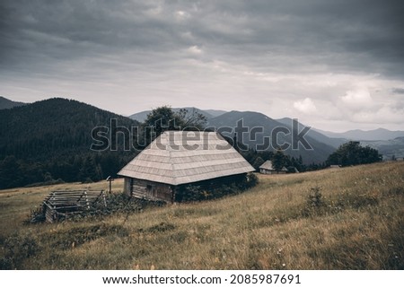 Picturesque autumn meadow with old wooden house and cloudy sky in the Carpathian mountains, Ukraine. Landscape photography
