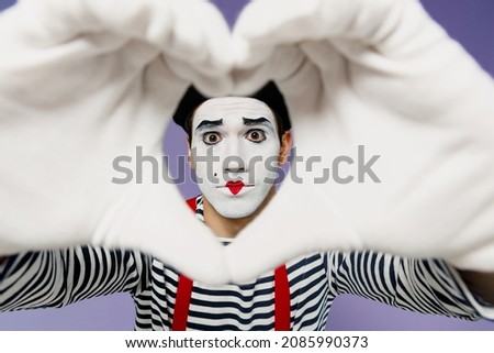 Close up vivid young mime man with white face mask wears striped shirt beret showing shape heart look through hands heart-shape sign isolated on plain pastel light violet background studio portrait
