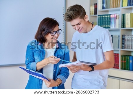 College student guy teenager meeting discussing with teacher mentor in classroom Royalty-Free Stock Photo #2086002793