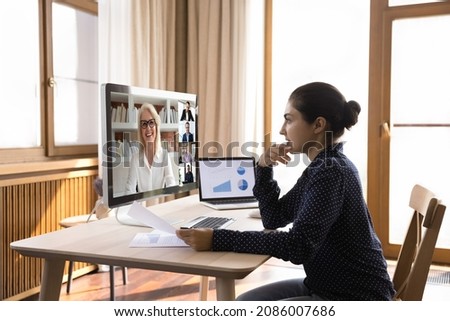 Focused Indian female young employee talking to boss and business team on online virtual conference chat, discussing project stats, reports, financial analytics with office coworkers on video call Royalty-Free Stock Photo #2086007686