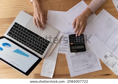 Top view close up woman accountant counting taxes, young female hands typing on laptop keyboard and calculator, calculating domestic budget, working on financial report, analyzing statistics Royalty-Free Stock Photo #2086007722