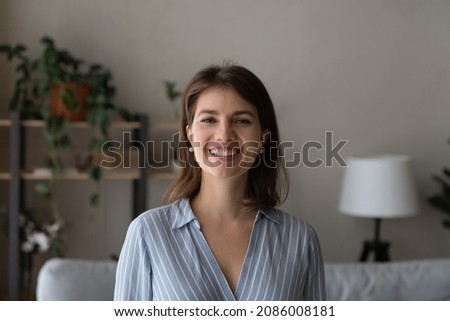 Happy young woman in casual head shot portrait. Smiling positive female homeowner, tenant lady, renter housewife enjoying being at home, looking at camera, laughing. Front view