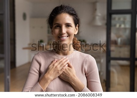 Head shot portrait smiling woman folded hands on chest, feeling love and grateful, happy young female expressing gratitude, thanking god and faith, making wish, charity and support concept Royalty-Free Stock Photo #2086008349