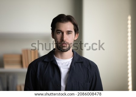 Confident handsome 30s Caucasian millennial man, businessman, self employed professional in home office interior. Millennial guy in casual black shirt looking at camera. Head shot portrait
