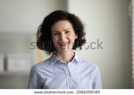 Happy confident mature businesswoman indoor head shot. Elder professional teacher, coach, boss looking at camera with toothy smile. Female business leader portrait. Leadership concept