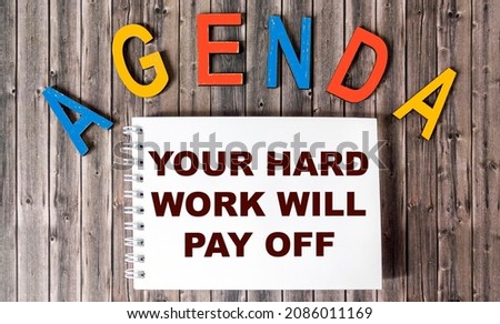 Your hard work will pay off with inspiring text on notepad and wooden desk. AGENDA is written on the table in wooden letters