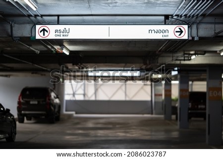 Carparking Lighting box is hung on ceiling. Thai Laungae letter on lighting box at the left side mean "ONE WAY" and right side mean "EXIT".