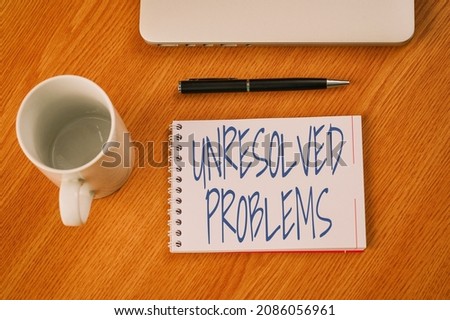 Conceptual caption Unresolved Problems. Word for those Queries no one can answer Unanswerable Questions Closed Laptop Beside Empty Journal With Pen And Coffee Mug Over Table.