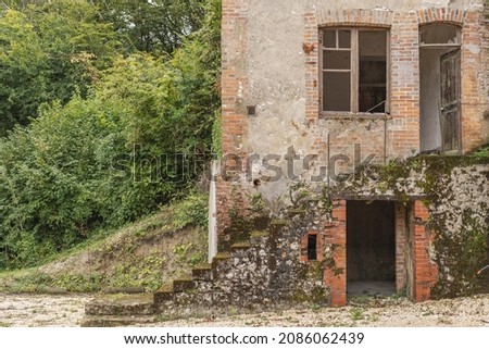 A old european house which is abandoned with the door wide open and steps leading upwards as well as a cellar