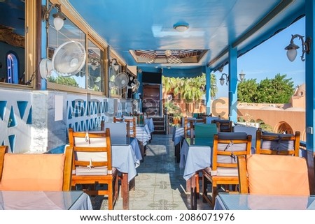 Interior of a fish restaurant open terrace decorated in a blue colour. Spacious restaurant hall is empty, there are no visitors at the tables. Terrace offers city views Royalty-Free Stock Photo #2086071976
