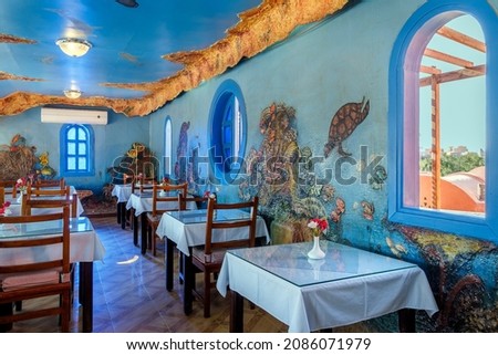 Interior of a fish restaurant decorated in a blue colour. Spacious restaurant hall is empty, there are no visitors at the tables. Large windows offer city views Royalty-Free Stock Photo #2086071979
