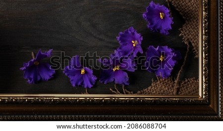 Part of a beautiful frame contains rough weave fabric on a wooden background and violet flowers. Background for the inscription.