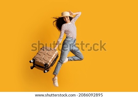 Time To Travel. Full Length Shot Of Cheerful Excited Young Woman Wearing Wicker Hat Jumping With Suitcase Over Yellow Background, Happy Tourist Lady Ready For Summer Vacation Trip, Copy Space Royalty-Free Stock Photo #2086092895