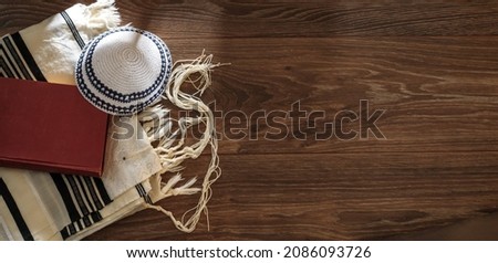 Jewish traditional prayer supplies. Talite, kippah, torah on a wooden table. Shabbatt, Bar Mitzvah, Yom kippur concept. Long horizontal banner Royalty-Free Stock Photo #2086093726